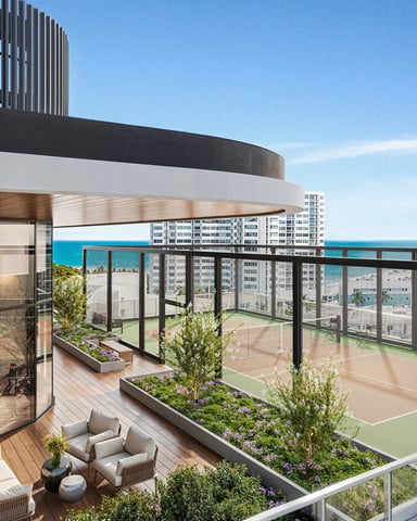 Modern rooftop terrace with seating area, planters, and ocean view beyond residential buildings and sports courts