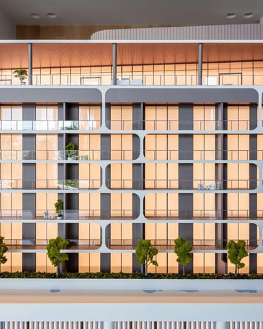 Modern multi-story residential building with rounded balconies, gridded windows, and small trees at street level