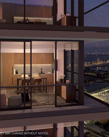 Modern high-rise apartment with floor-to-ceiling windows overlooking illuminated waterfront city at dusk